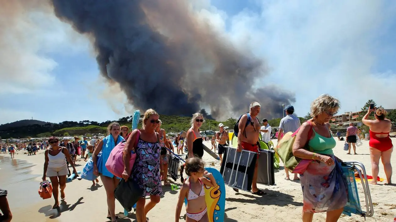 Vacanciers évacuant une plage à proximité d'un feu de forêt