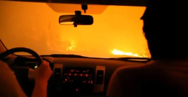 Vue depuis l'intérieur d'une voiture face à une route enfumée par un incendie de forêt